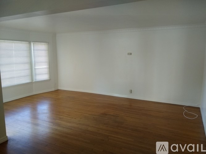 A room with wooden flooring and a window with blinds.