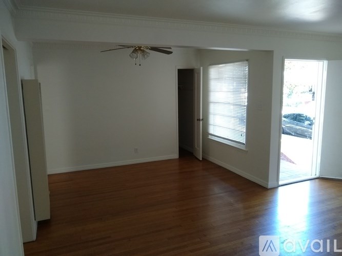 A room with a ceiling fan and wooden floors.