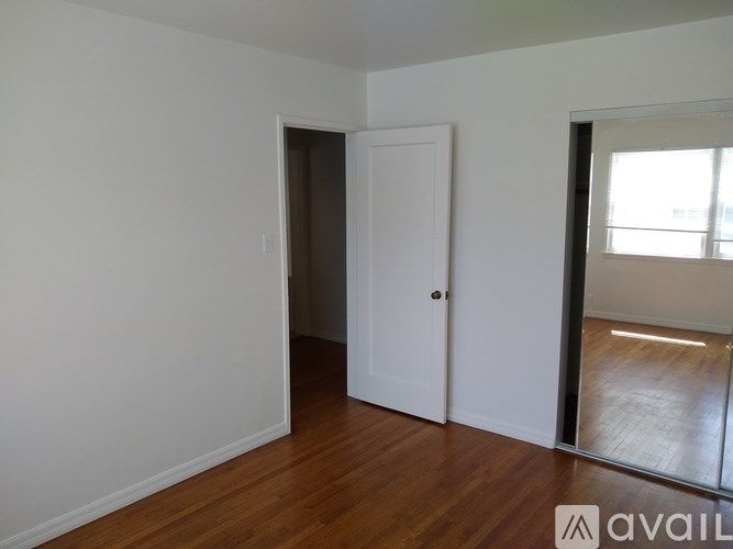 A room with a white door and wooden floor.