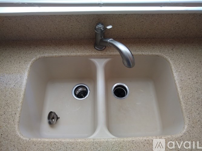 A double sink with a faucet and two drain holes.