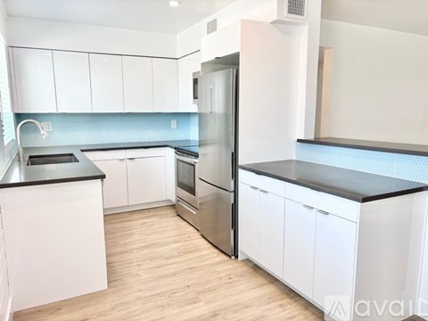 A kitchen with white cabinets and a black countertop.