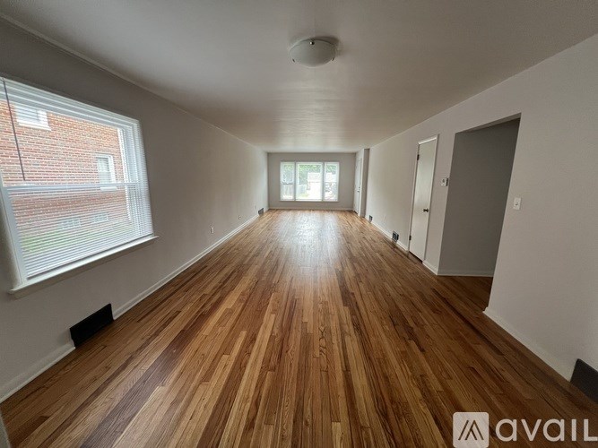 A room with wooden flooring and a window on the left side.