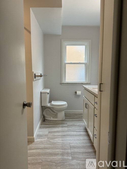A bathroom with a toilet, sink, and a window.