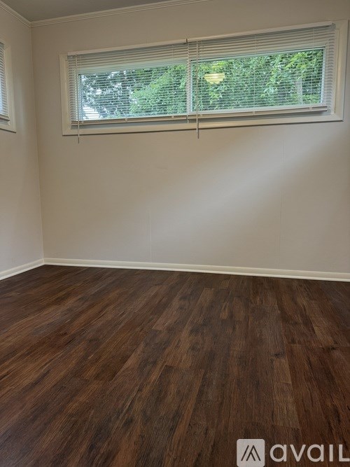 A room with wooden flooring and a window with blinds.