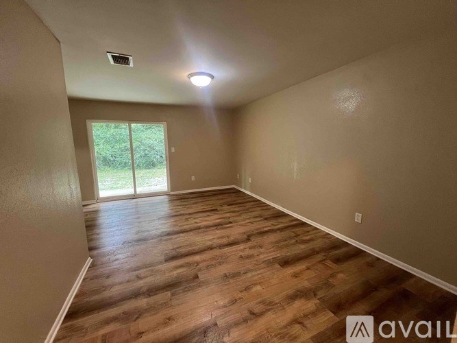 A room with wooden flooring and a window overlooking greenery.