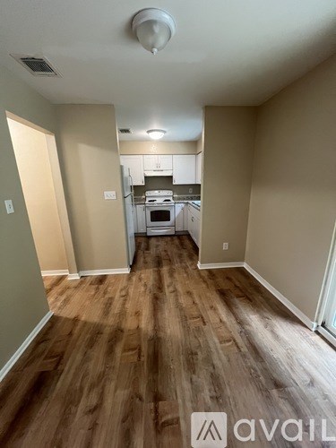 A kitchen area with wooden floors and a white ceiling.