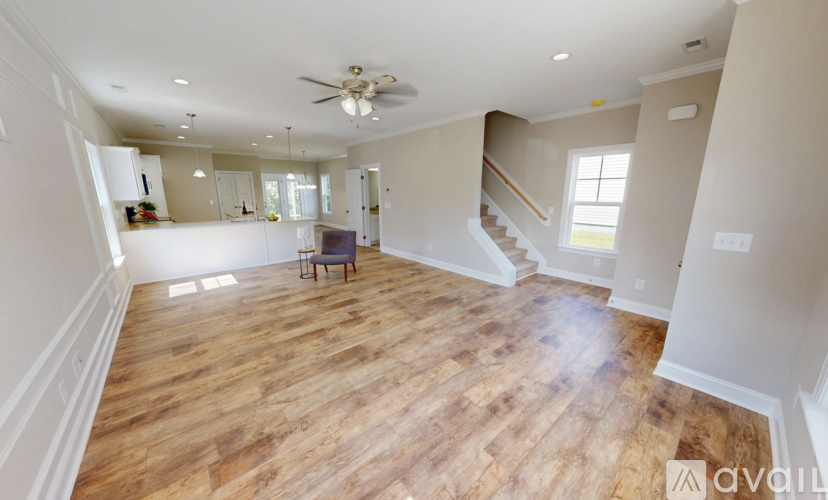 A spacious living room with wood flooring and a ceiling fan.