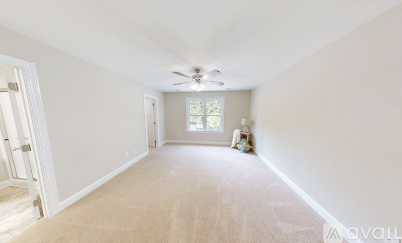 A spacious room with a carpeted floor and a ceiling fan.