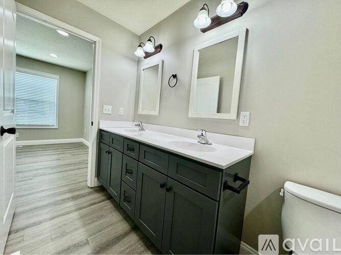 A bathroom with a vanity, two mirrors, and a toilet.
