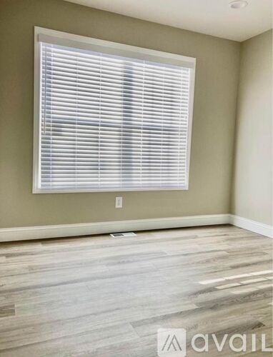 A room with a window covered in blinds and wooden flooring.