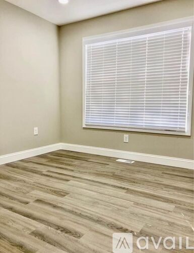 A room with wooden flooring and a window with blinds.
