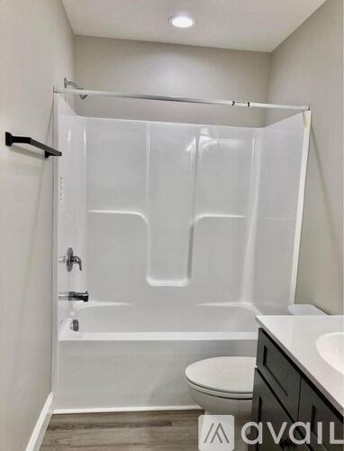 A bathroom with a white shower, toilet, and sink.