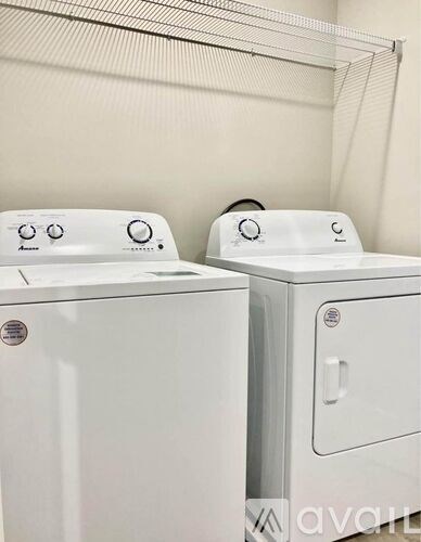 Two white front loading washing machines in a laundry room.