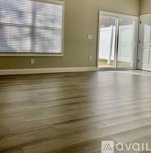 A room with wooden flooring and a window with blinds.