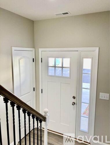 A white door with a window in the middle is in a room with a wooden staircase.