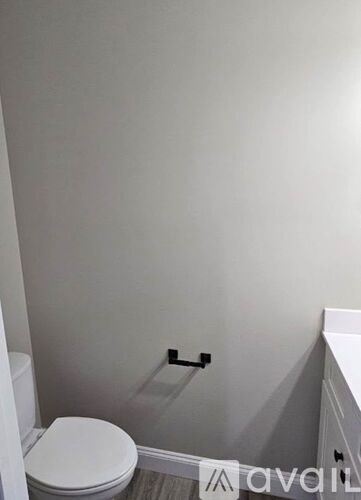 A white toilet in a small bathroom with a grey wall.