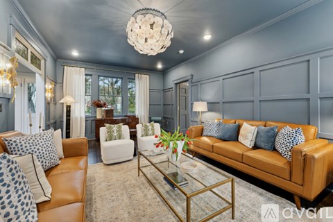 A living room with a brown leather couch and a glass coffee table.
