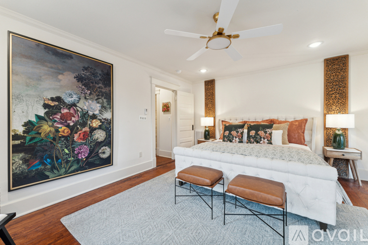 A bedroom with a large bed and a painting on the wall.