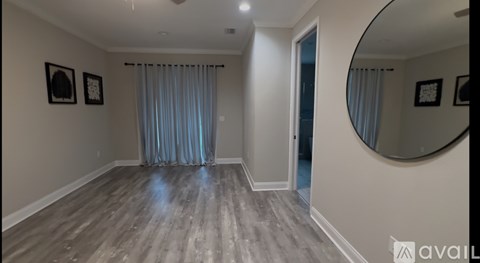 A room with wooden flooring and a round mirror on the wall.
