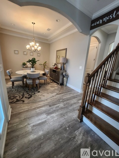 A dining room with a table set for four and a chandelier hanging from the ceiling.