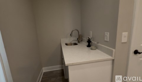 A small white sink in a corner of a room.
