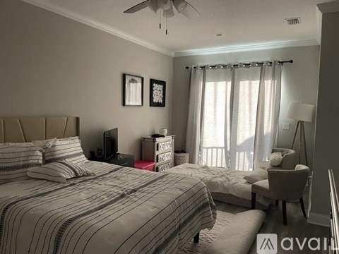 A bedroom with a large bed and a chair by the window.