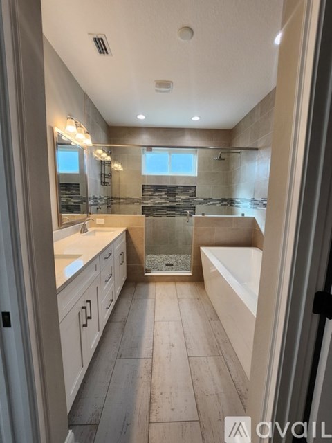 A bathroom with a tub, sink, and mirror.