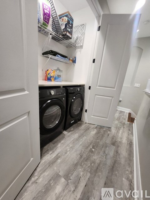 A laundry room with two front-loading washing machines and a shelf above them.