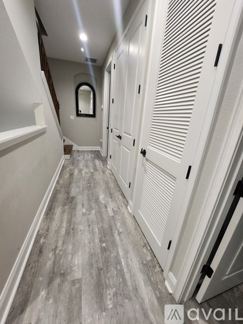 A hallway with white doors and a wooden floor.