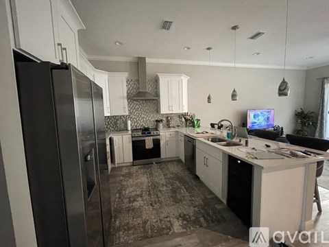 A kitchen with a refrigerator, sink, and cabinets.