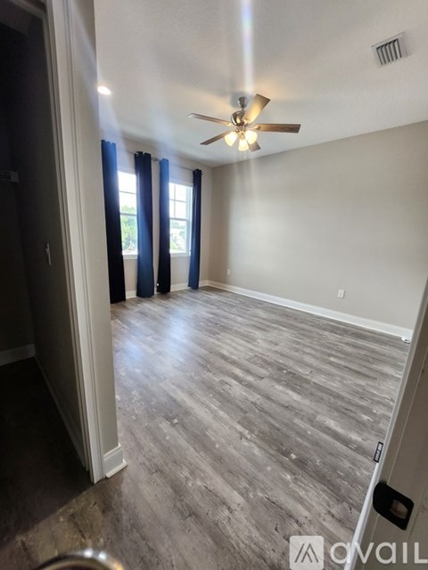 A room with a ceiling fan and sliding glass doors.