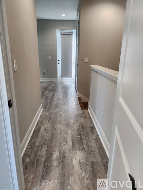 A hallway with wood flooring and white walls.