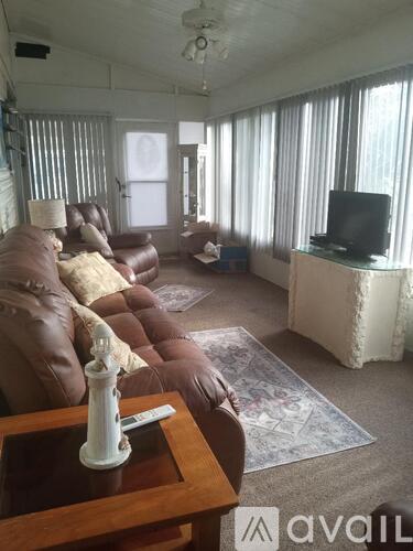 A living room with a brown couch and a television on a white stand.