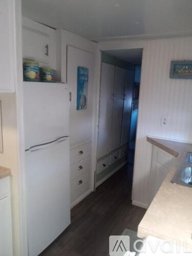 A kitchen with white cabinets and a white fridge.