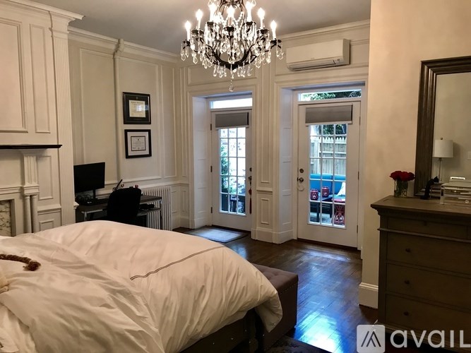 A bedroom with a large bed and a chandelier.