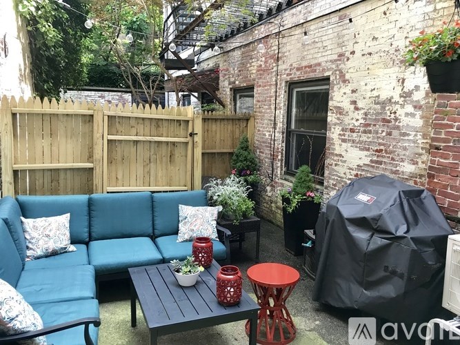 A blue couch with a wooden fence and a grill in the backyard.