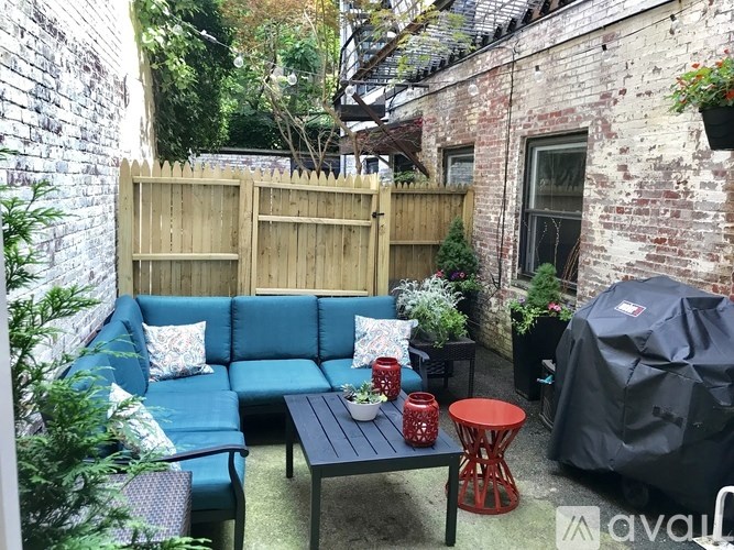 A patio with a blue couch, a table, and a red stool.
