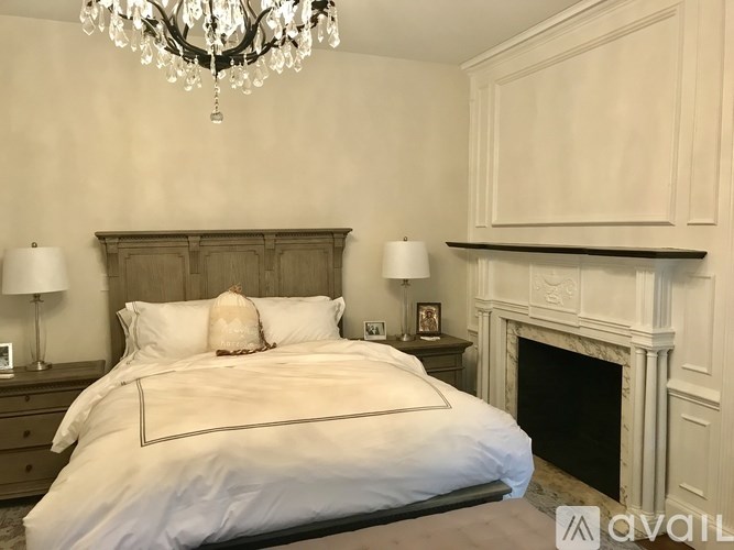 A bedroom with a large bed, a chandelier, and a fireplace.