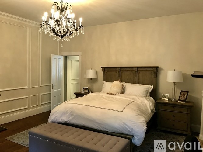 A bedroom with a large bed and a chandelier.