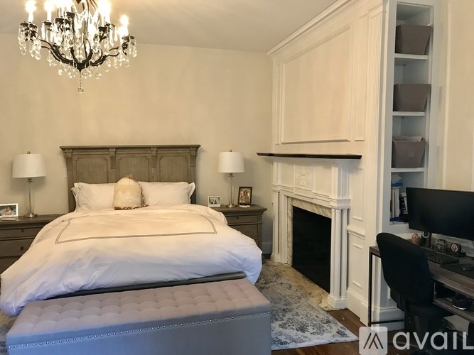 A bedroom with a large bed, a fireplace, and a chandelier.