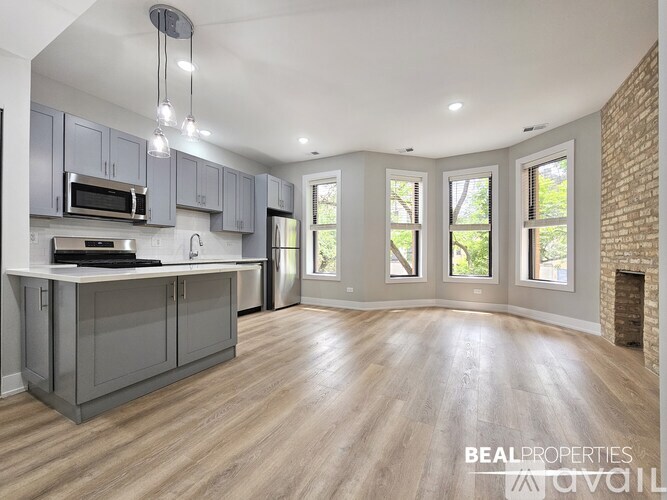 A spacious kitchen with wooden floors and grey cabinets.