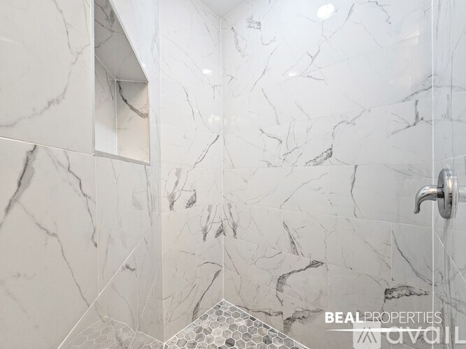 A white marble bathroom with a shower and a towel rack.