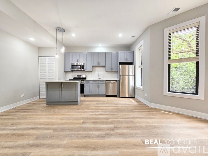 A spacious kitchen with grey cabinets and a wooden floor.