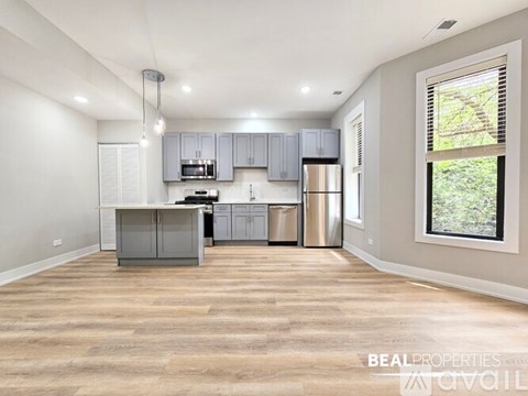 A spacious kitchen with grey cabinets and a wooden floor.