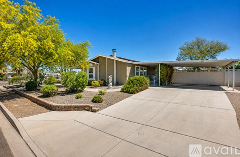 A house with a driveway and a tree with yellow leaves.