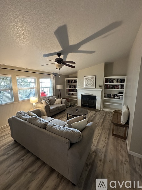 A living room with a grey sofa and a ceiling fan.