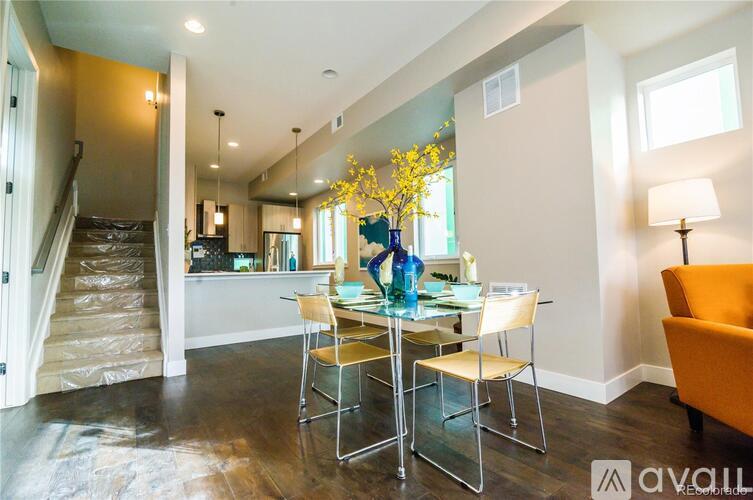 A dining room with a glass table and chairs and a staircase in the background.