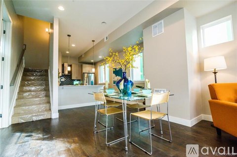 A dining room with a glass table and chairs and a staircase in the background.