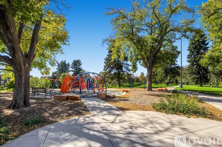 A playground with a slide and a bench is surrounded by trees.