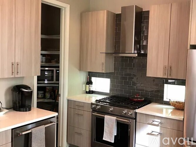 A kitchen with a black stove top oven and a black coffee maker on the counter.